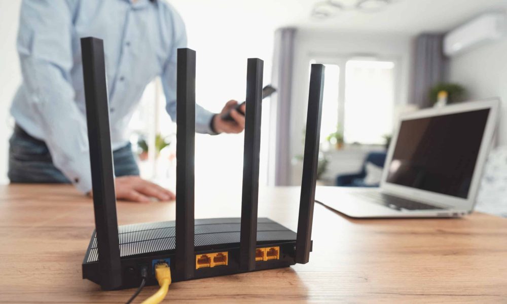 Man using modern wi-fi router on light table in room Man using modern wi-fi router on light table in room
